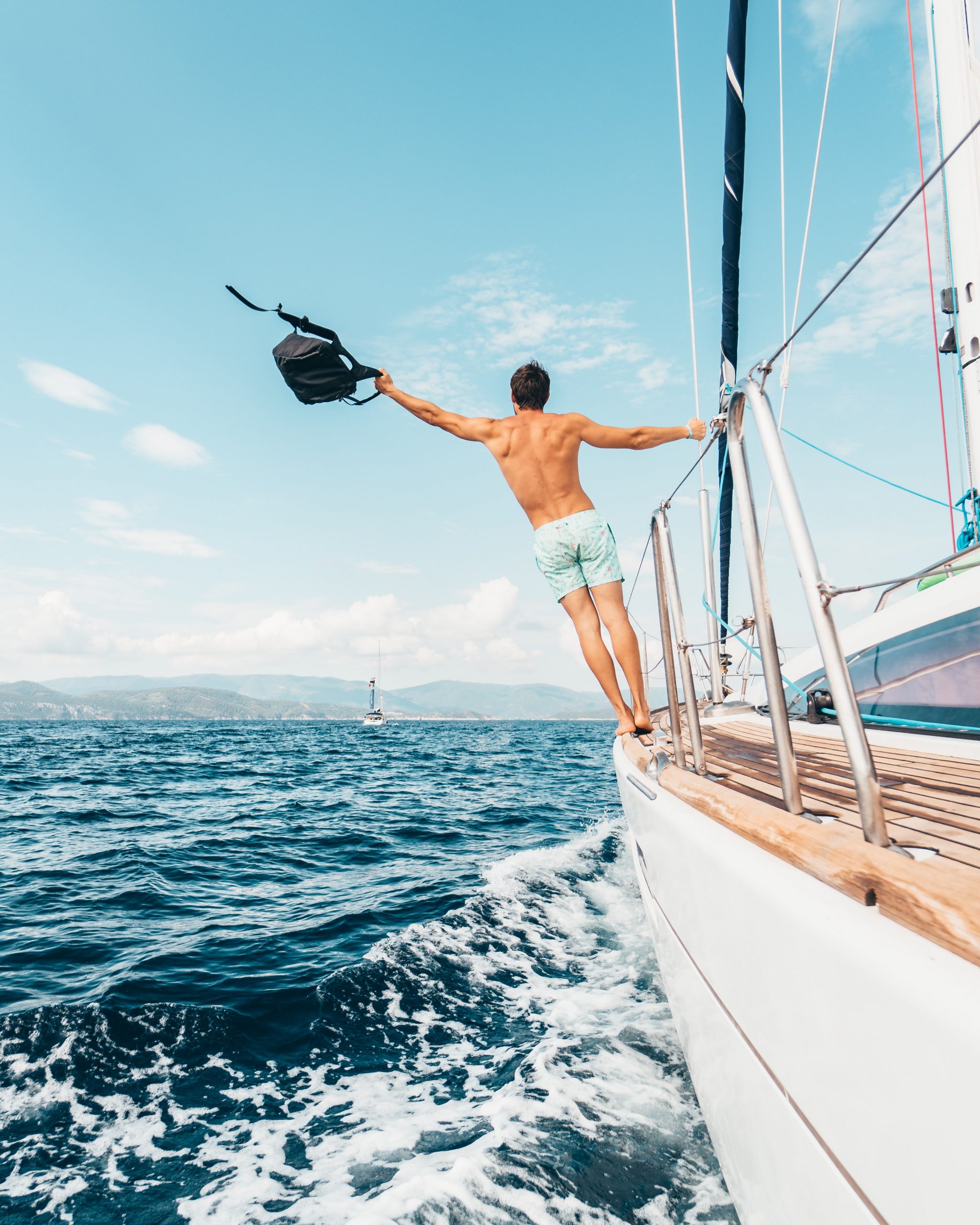 man hanging off the side of a yacht